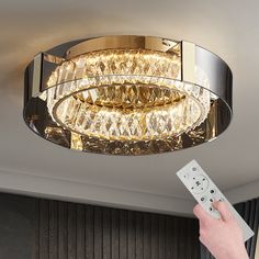 a person is holding a remote control in front of a chandelier with lights