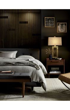 a bedroom with a bed, nightstands and pictures on the wall above it in dark colors