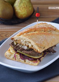 a sandwich on a plate with pears in the background