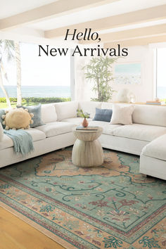 a living room with white couches and rugs next to large windows overlooking the ocean