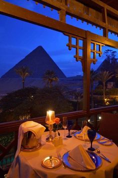 the table is set for two with an egyptian pyramid in the background at night time