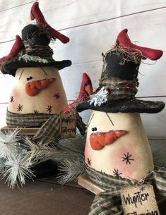 two snowmen with hats and scarves on their heads are sitting next to each other