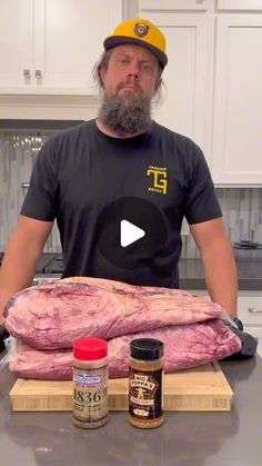 a man standing in front of a cutting board with raw meat on top of it