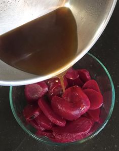 a bowl filled with sliced beets being drizzled on top of it