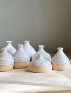 several white vases sitting on top of a wooden table