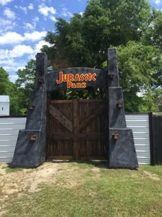 the entrance to jurasic park is made out of wood and stone, with an iron gate