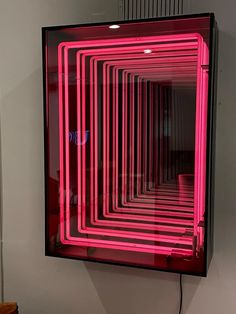 a pink neon light is in the middle of a room with white walls and flooring