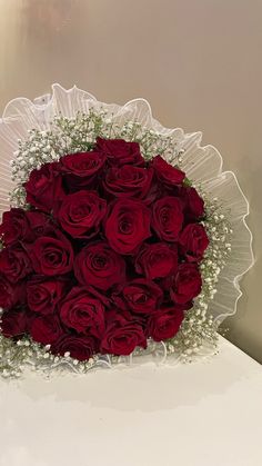 a bouquet of red roses on a white table