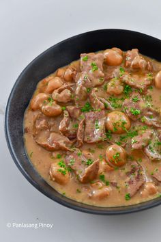 a black bowl filled with meat and beans