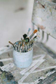 the paintbrushes are sitting in the cup on the chair