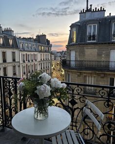 a vase with flowers sitting on top of a table next to a balcony overlooking the city