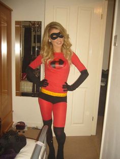 a woman in a red and black costume standing next to a bed with her hands on her hips