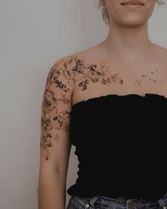 a woman with tattoos on her arm and shoulder is standing in front of a white wall