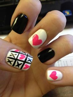 a woman's hand with black and white manies with pink hearts on them