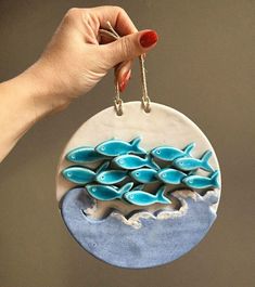 a hand holding a ceramic ornament with blue fish in the ocean on it