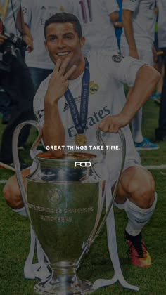 a man kneeling down next to a soccer trophy