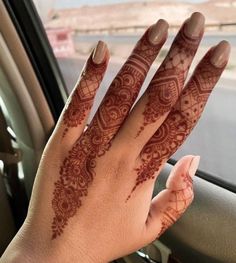 a woman's hand with henna on it in the passenger seat of a car