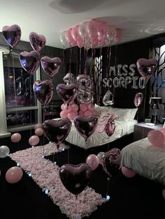 balloons are floating in the air near a bed with pink and black decorations on it