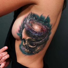 a tattoo with a skull and galaxy on it's side, in the shape of a spiral vortex