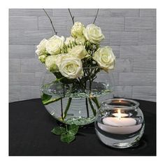 white roses in a glass vase with a lit candle