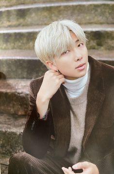 a young man sitting on the steps with his hand under his chin and looking up