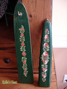 two green wooden boards with flowers painted on them sitting next to each other in front of a dresser