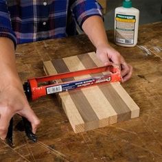 a person using a tool on a wooden board with glue and wood shavings