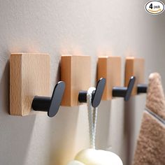 three wooden hooks are hanging on the wall next to a towel rack with soap and toothbrushes