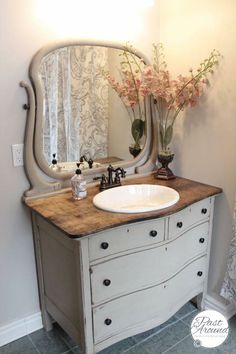 a bathroom vanity with a large mirror above it and flowers in vases on the counter