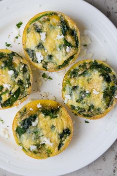 three small muffins with spinach and cheese on a white plate, ready to be eaten