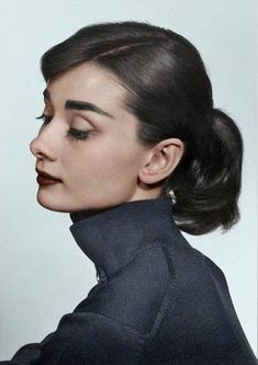 a woman with her hair in a high bun wearing a turtle neck sweater and earrings