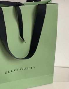 a green bag with the word gucci guilty on it