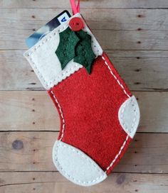 a felt christmas stocking hanging on a wooden wall with a tag attached to it