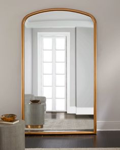 a large gold framed mirror sitting on top of a wooden floor next to a white door