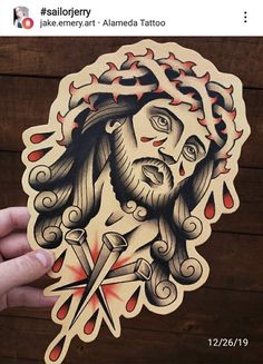 a hand holding up a sticker with a drawing of jesus and scissors on it