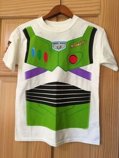 a t - shirt with the character buzz lightyear from toy story is hanging on a wooden door