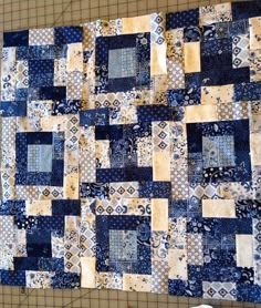 a blue and white patchwork quilt hanging on a wall next to a pair of scissors