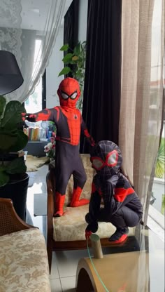 two children in spider man costumes standing on a couch