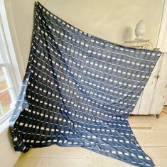 a blue and white blanket sitting on top of a wooden floor next to a window