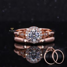 two rose gold wedding rings and an engagement ring on a black surface with reflections in the water