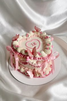 a heart shaped cake decorated with pink and white icing on top of a table