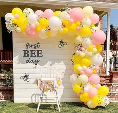 an arch made out of balloons with a sign that says first bee day