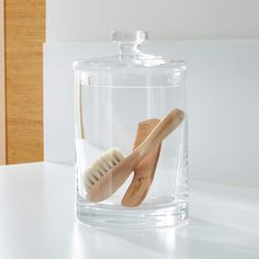 two wooden toothbrushes in a clear glass container