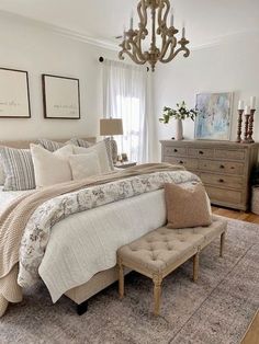 a bedroom with a large bed, chandelier and pictures on the wall above it