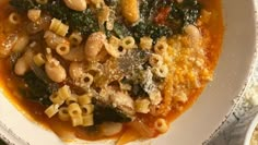 a white bowl filled with pasta and spinach