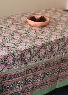 a bowl of pine cones sitting on top of a table covered in a green and red cloth