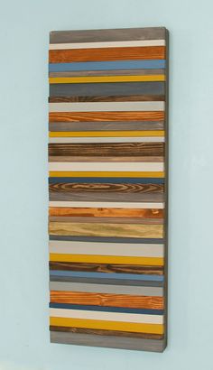 a wooden wall hanging on the side of a blue wall with multicolored stripes