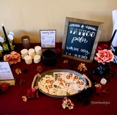 a table topped with lots of candles and flowers next to a sign that says tattoo parlor