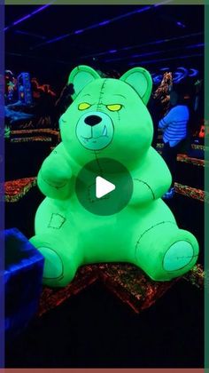 a large green teddy bear sitting in the middle of a room with other stuffed animals