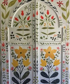 an intricately painted door with flowers and leaves on the outside, in front of a white wall